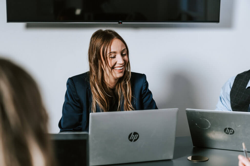 Image shows a teaching recruitment consultant with a laptop. They are smiling and looking at something off camera